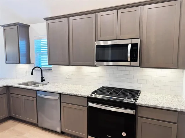 a kitchen with stainless steel appliances granite countertop a sink stove and microwave