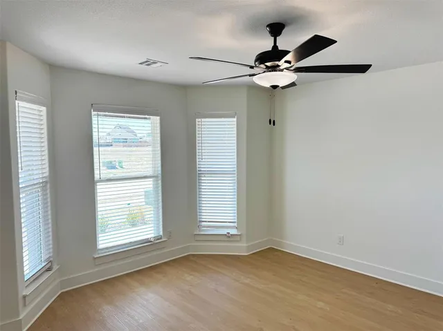 a view of empty room with wooden floor and fan