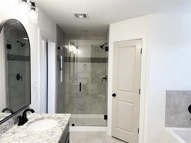 a bathroom with a granite countertop sink a mirror and shower