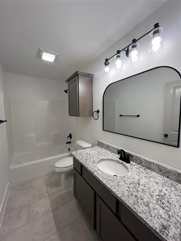 a bathroom with a granite countertop sink a toilet and mirror