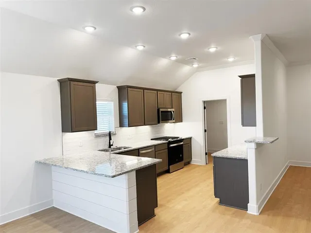 a kitchen with stainless steel appliances granite countertop a sink and a refrigerator