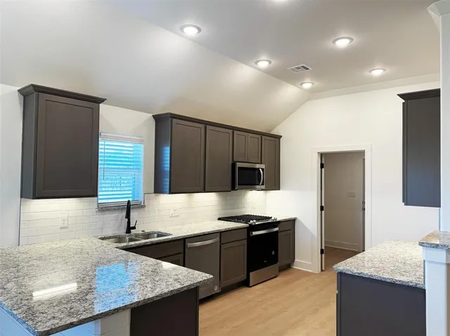 a large kitchen with kitchen island granite countertop a sink and a stove
