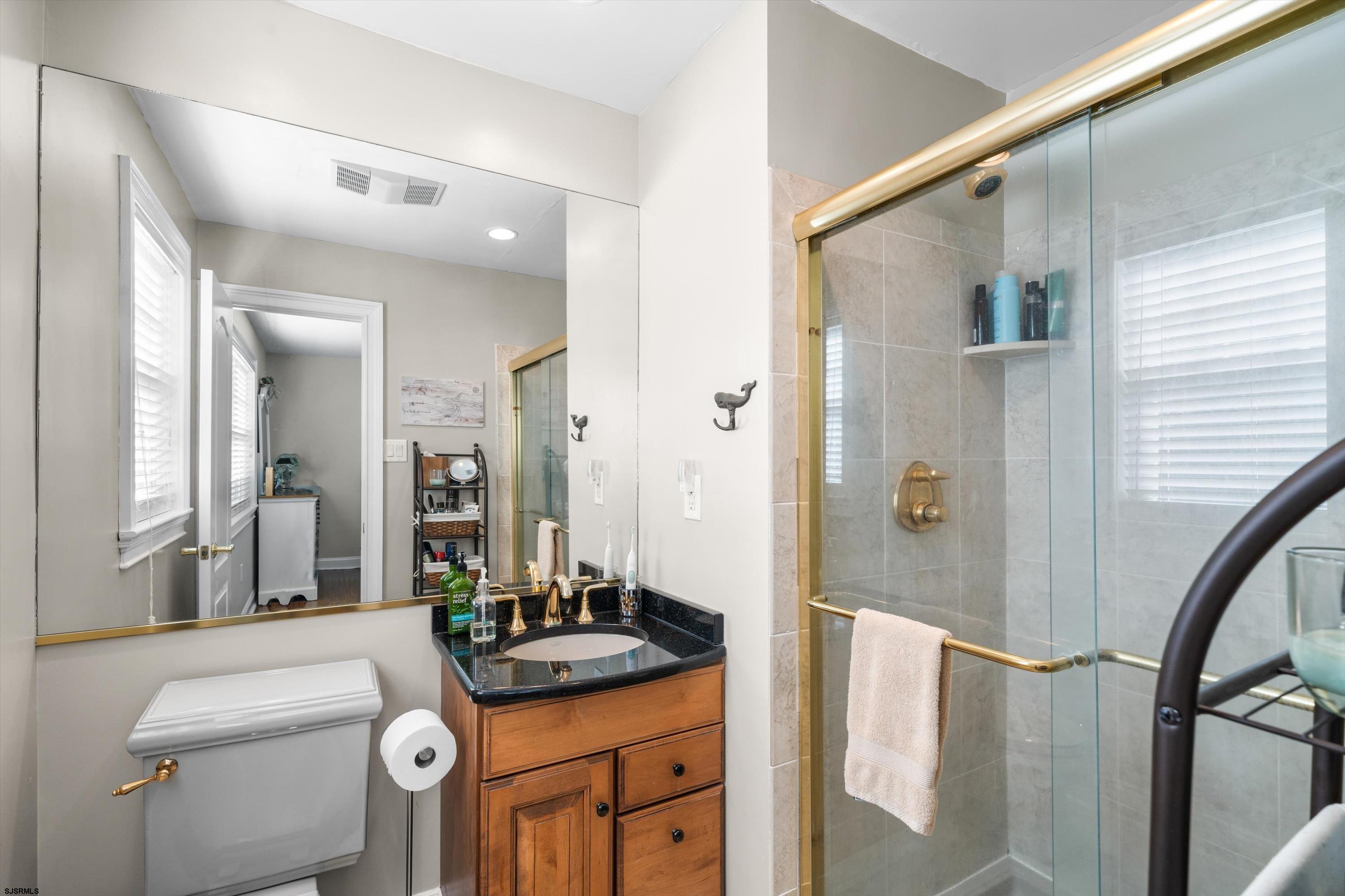 51 Simpson Road, Unit 2 Ocean City, NJ 08226 - Photo 34 of 43 a bathroom with a granite countertop sink a toilet a mirror and shower