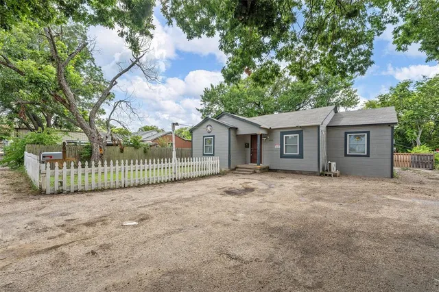 a view of a house with a backyard and a large tree