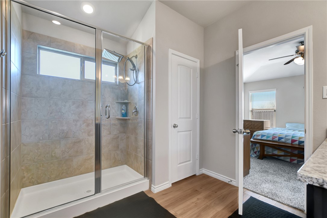 909 Davy Street Brenham, TX 77833 - Photo 21 of 35 Full bathroom with a stall shower, light wood-style flooring, ensuite bathroom, and healthy amount of natural light
