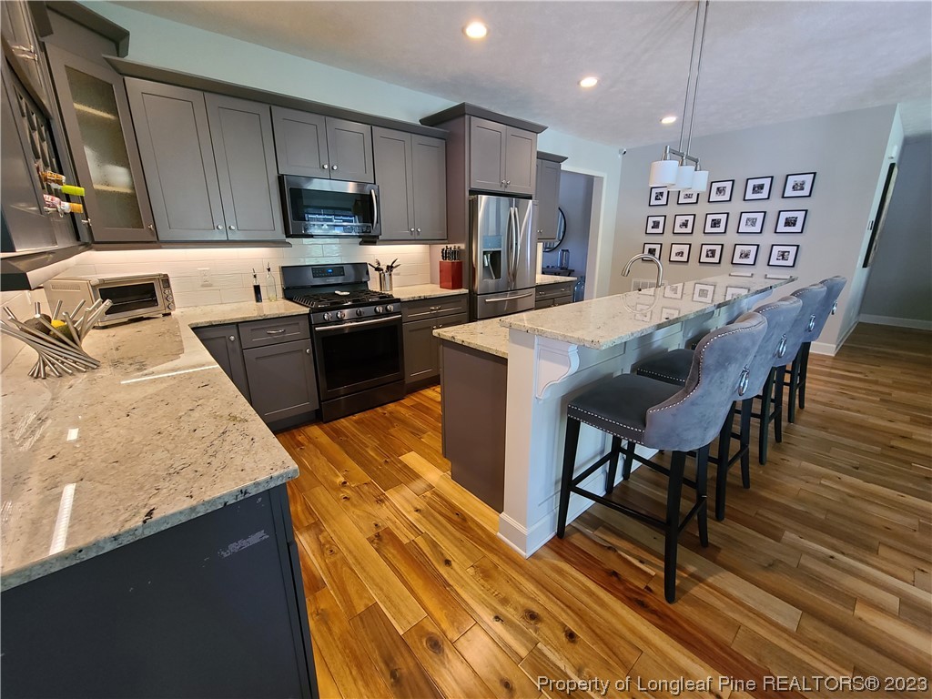 215 Devon Circle Aberdeen, NC 28315 - Photo 12 of 35 a kitchen with granite countertop kitchen island stainless steel appliances a sink a stove a refrigerator a microwave a dining table and chairs