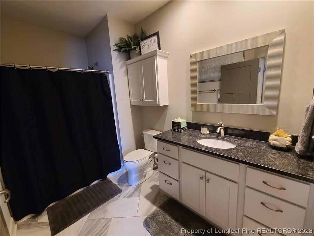 215 Devon Circle Aberdeen, NC 28315 - Photo 26 of 35 a bathroom with a granite countertop sink toilet and mirror