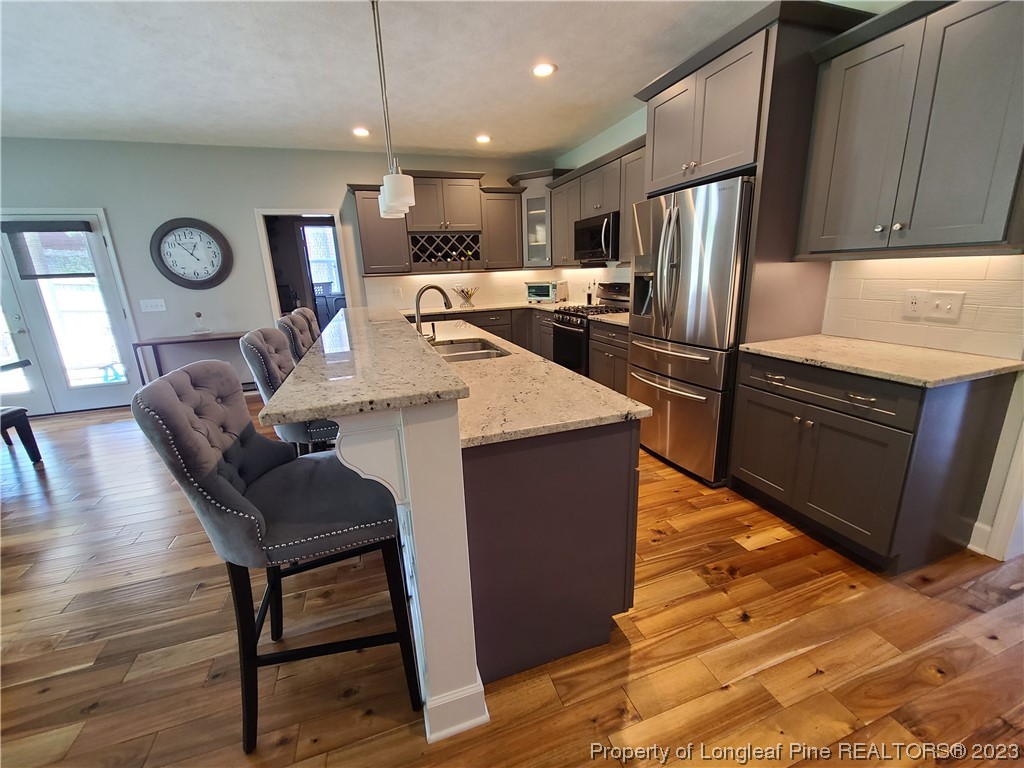 215 Devon Circle Aberdeen, NC 28315 - Photo 10 of 35 a kitchen with granite countertop a refrigerator a stove top oven a dining table and chairs with wooden floor