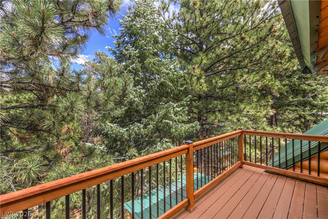 322 Ski Trail Road Mount Charleston, NV 89124 - Photo 41 of 58 An elevated wood deck overlooks a serene and dense forest canopy.
