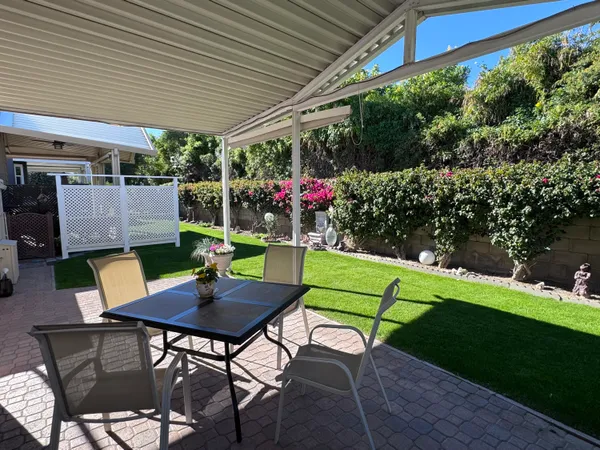a view of a chairs and table in patio next to a yard