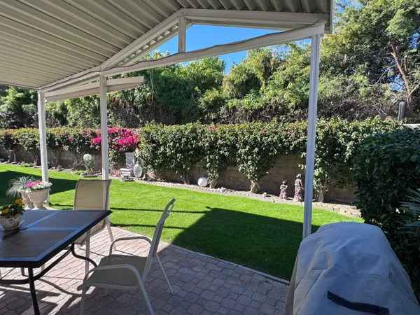 a view of a chairs and table in patio next to a yard