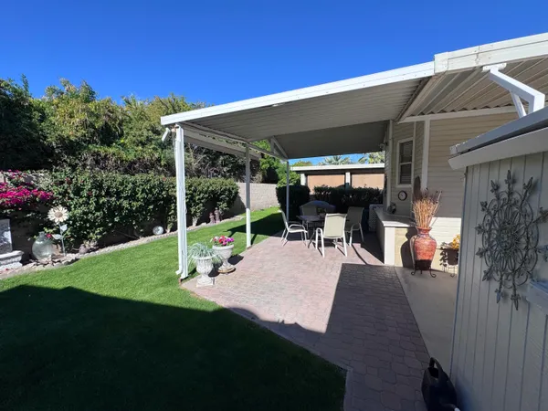 a view of a patio with table and chairs potted plants and floor to ceiling window