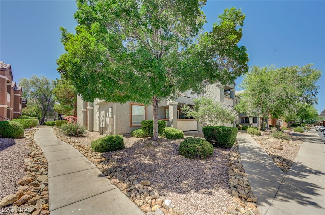 555 East Silverado Ranch Boulevard, Unit 2124 Las Vegas, NV 89183 - Photo 5 of 47 Discover a welcoming property with a well-maintained pathway, mature trees, and attractive landscaping.