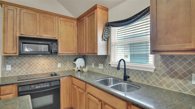a kitchen with granite countertop a sink stove and cabinets