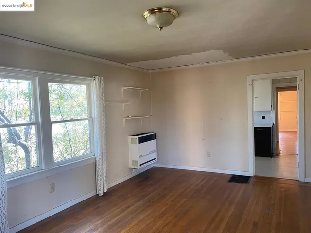 a view of kitchen and empty room with wooden floor