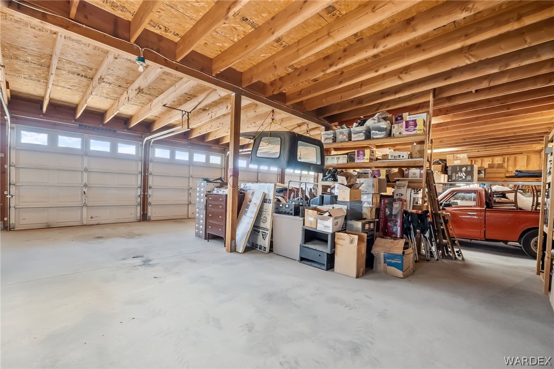 2401 North Stephan Road Kingman, AZ 86401 - Photo 75 of 92 Spacious garage featuring two overhead doors with transom windows, exposed wood beam ceiling, and concrete flooring