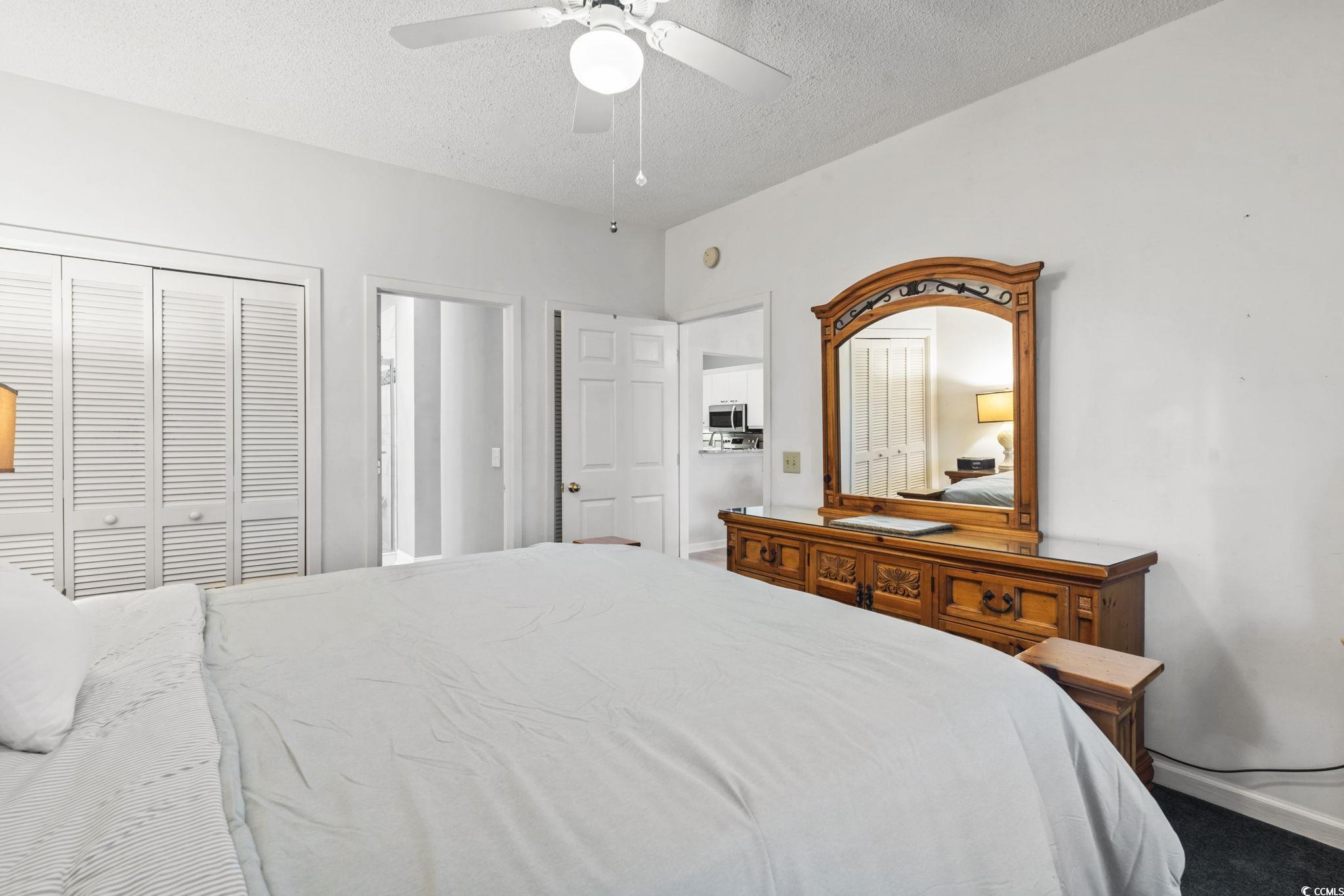104 High Circle, Unit 8C Myrtle Beach, SC 29572 - Photo 17 of 36 Bedroom featuring a textured ceiling, a closet, a ceiling fan, carpet and an ensuite bath