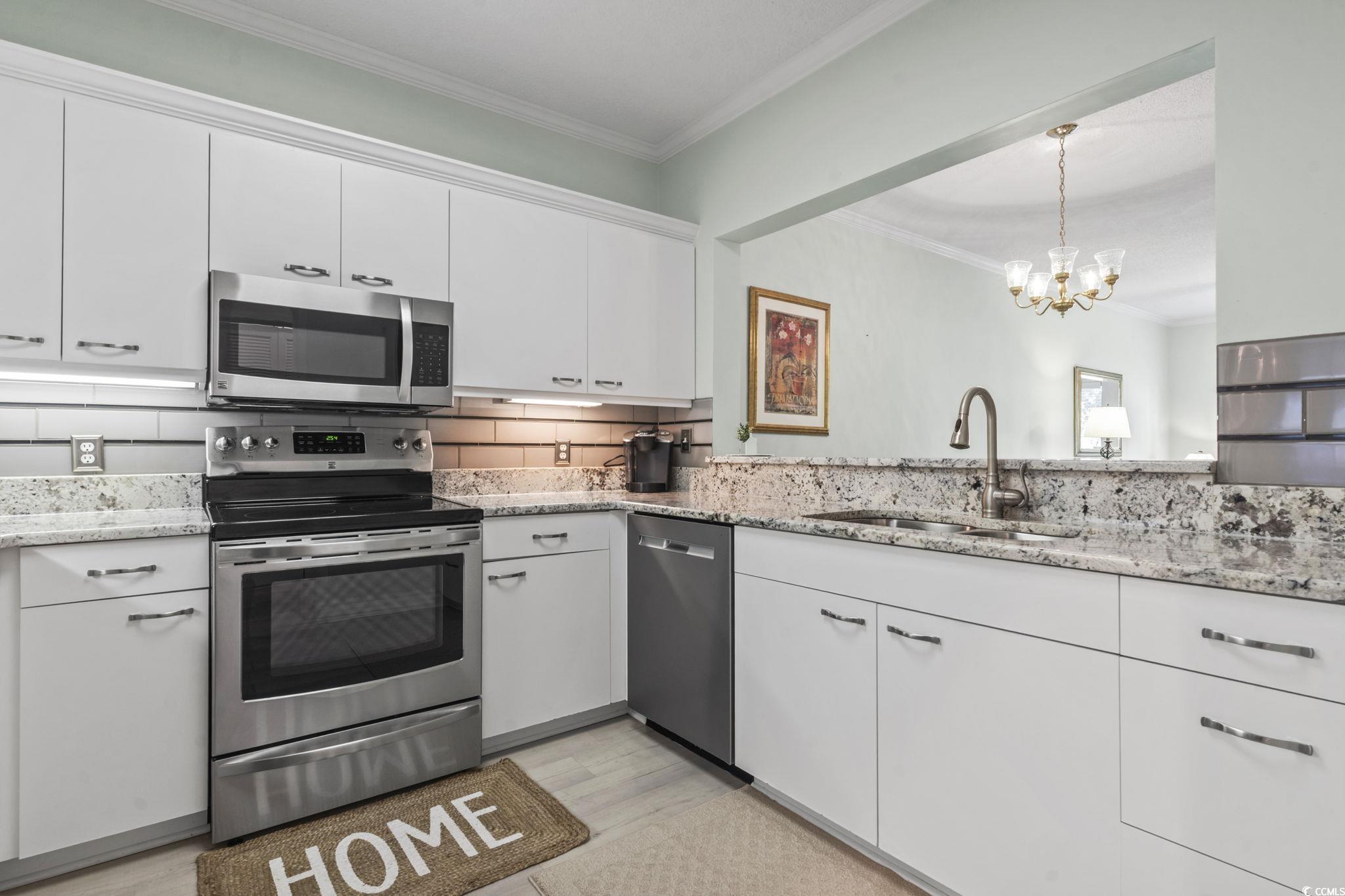 104 High Circle, Unit 8C Myrtle Beach, SC 29572 - Photo 23 of 36 Kitchen with crown molding, white cabinetry, stainless steel appliances, decorative backsplash, and decorative light fixtures