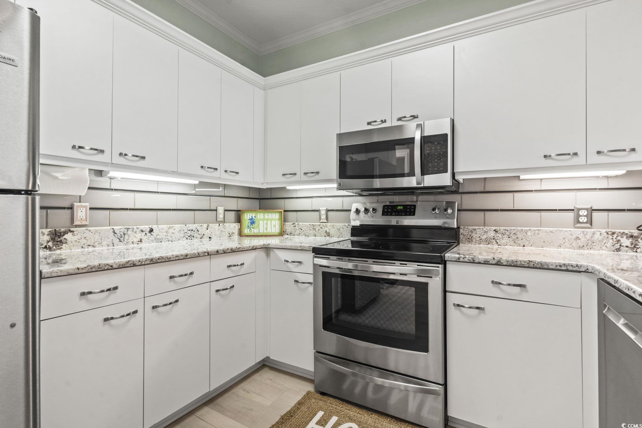 104 High Circle, Unit 8C Myrtle Beach, SC 29572 - Photo 24 of 36 Kitchen with stainless steel appliances, white cabinets, crown molding, light wood-style flooring, and tasteful backsplash