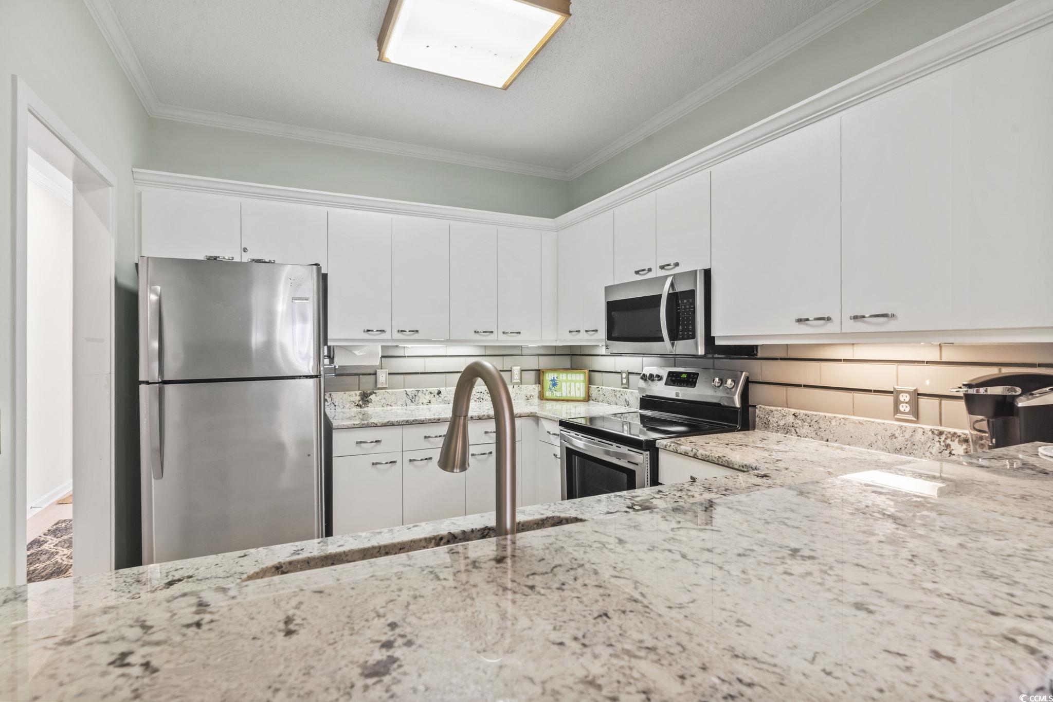 104 High Circle, Unit 8C Myrtle Beach, SC 29572 - Photo 26 of 36 Kitchen featuring ornamental molding, stainless steel appliances, white cabinetry, light stone counters, and decorative backsplash