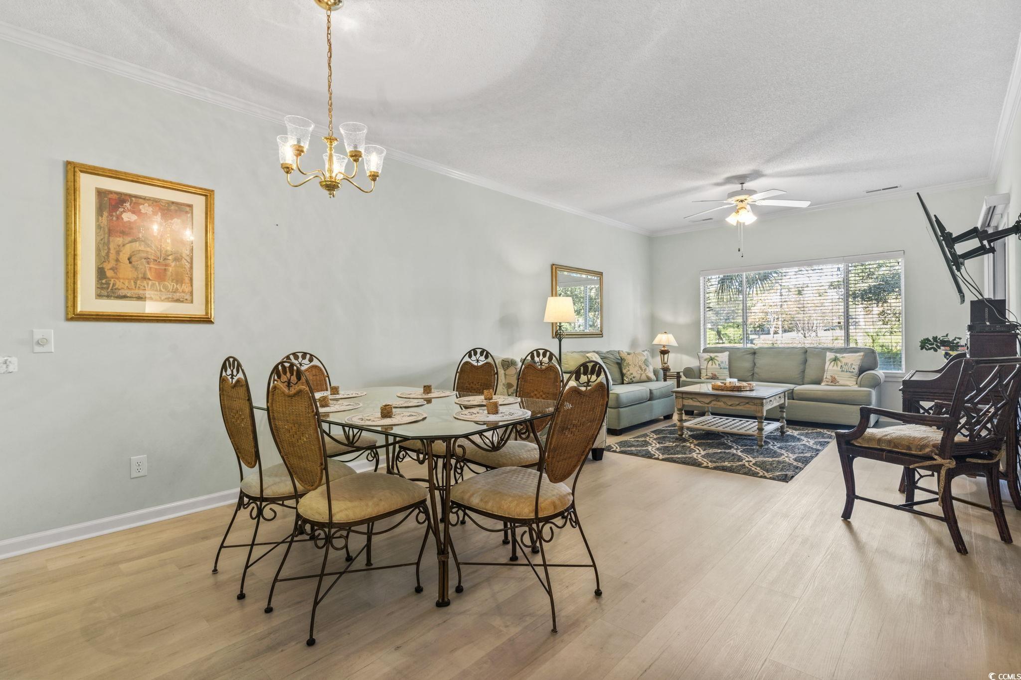 104 High Circle, Unit 8C Myrtle Beach, SC 29572 - Photo 27 of 36 Dining area featuring ornamental molding, light wood-style floors, a textured ceiling, a ceiling fan, and a chandelier