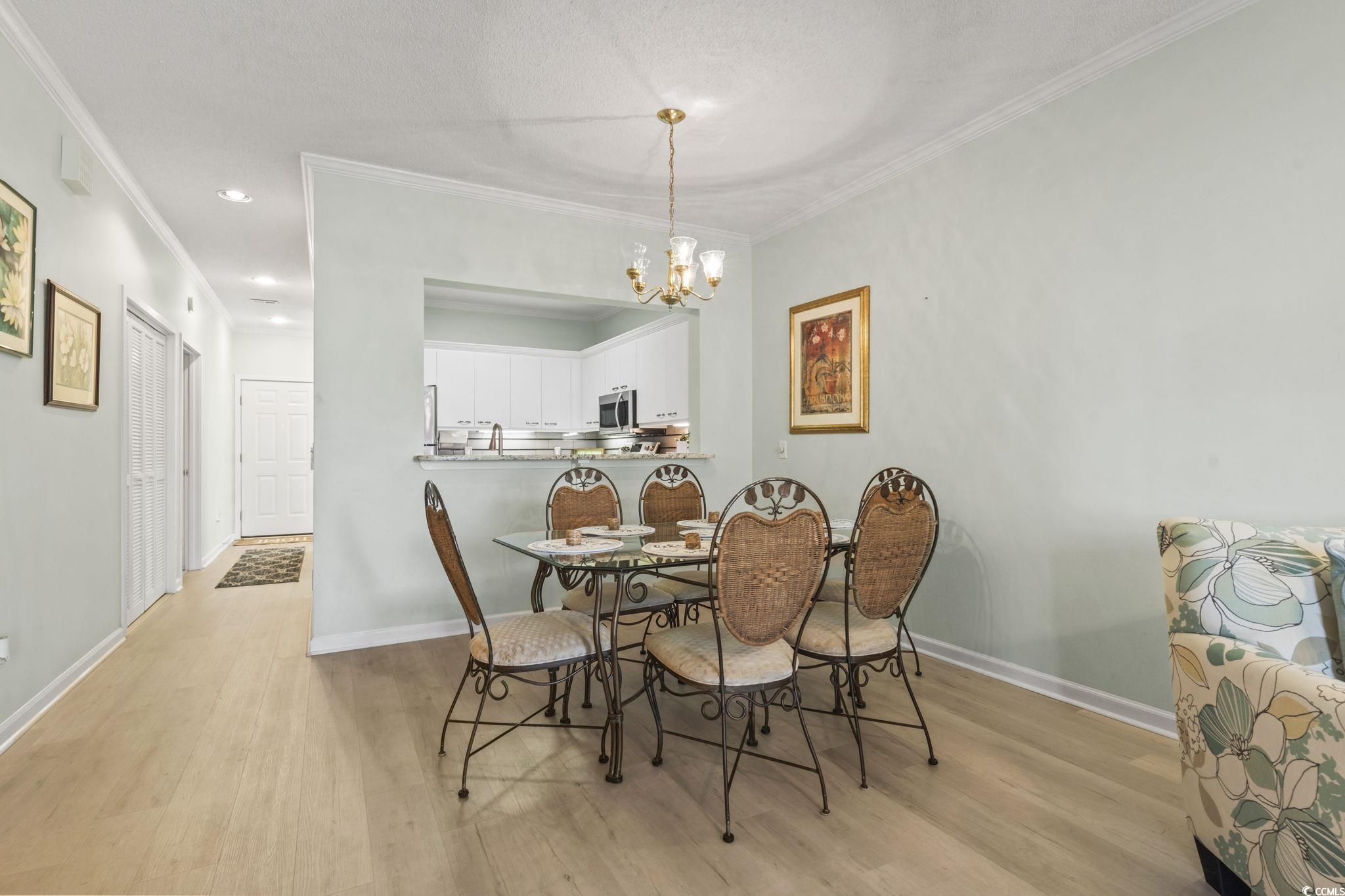 104 High Circle, Unit 8C Myrtle Beach, SC 29572 - Photo 28 of 36 Dining area with light wood-type flooring, a chandelier, crown molding, and chandelier lighting