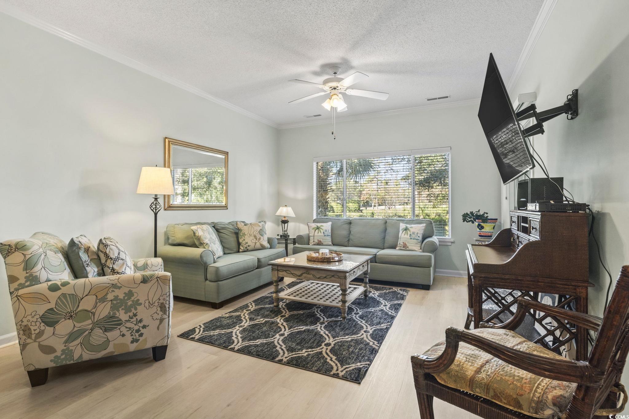 104 High Circle, Unit 8C Myrtle Beach, SC 29572 - Photo 29 of 36 Living room with ornamental molding, light wood-style floors, plenty of natural light, a textured ceiling, and a ceiling fan