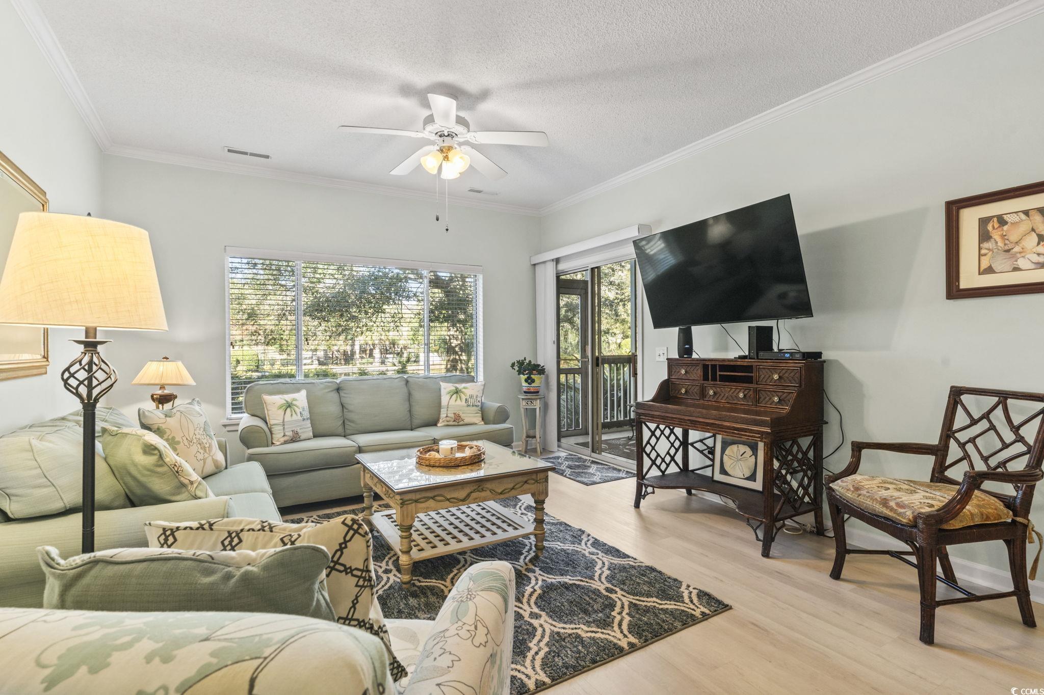 104 High Circle, Unit 8C Myrtle Beach, SC 29572 - Photo 30 of 36 Living area with wood finished floors, ornamental molding, a textured ceiling, and a ceiling fan