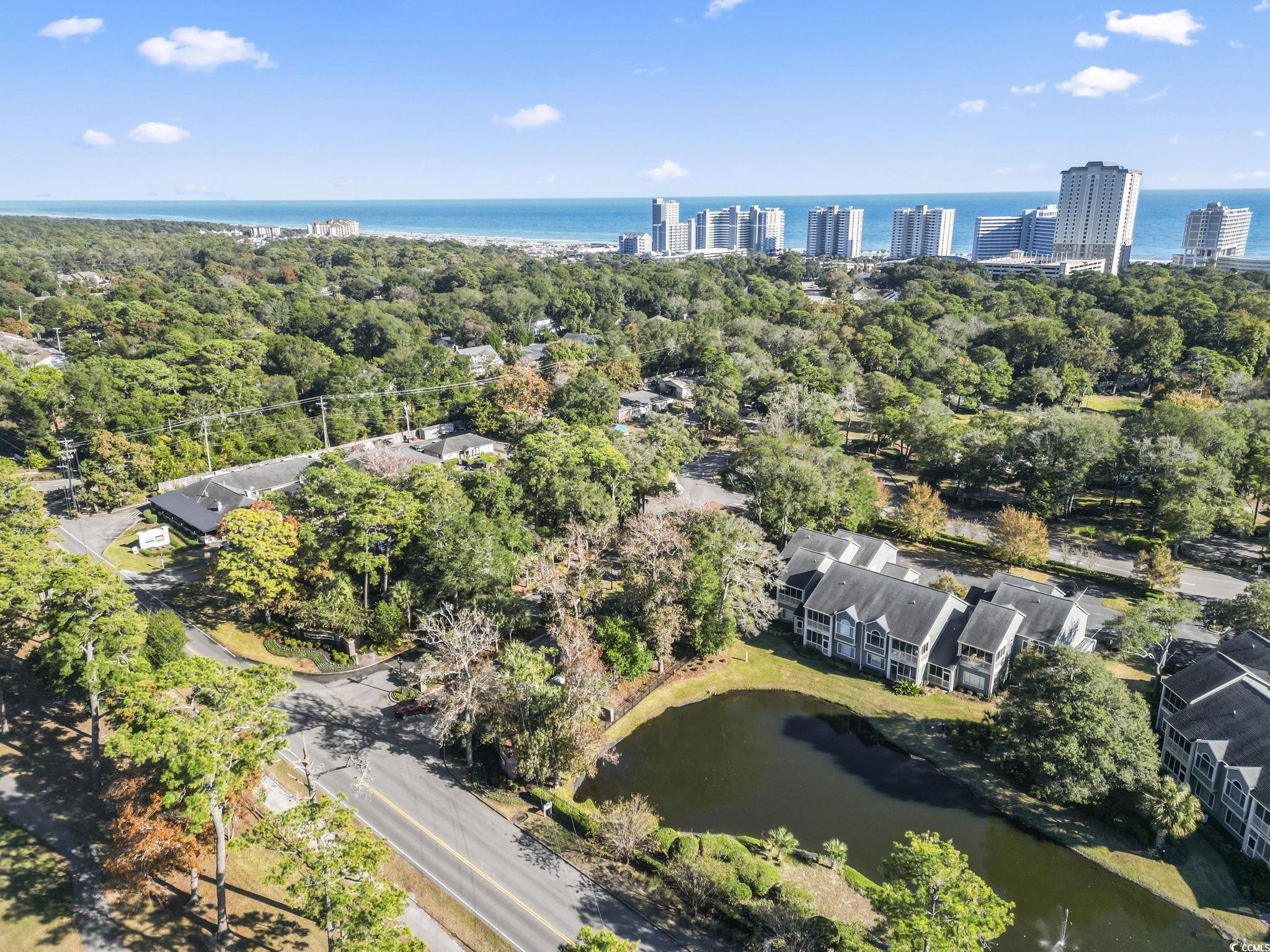 104 High Circle, Unit 8C Myrtle Beach, SC 29572 - Photo 9 of 36 Aerial view of property's location with a large body of water and a tree filled landscape