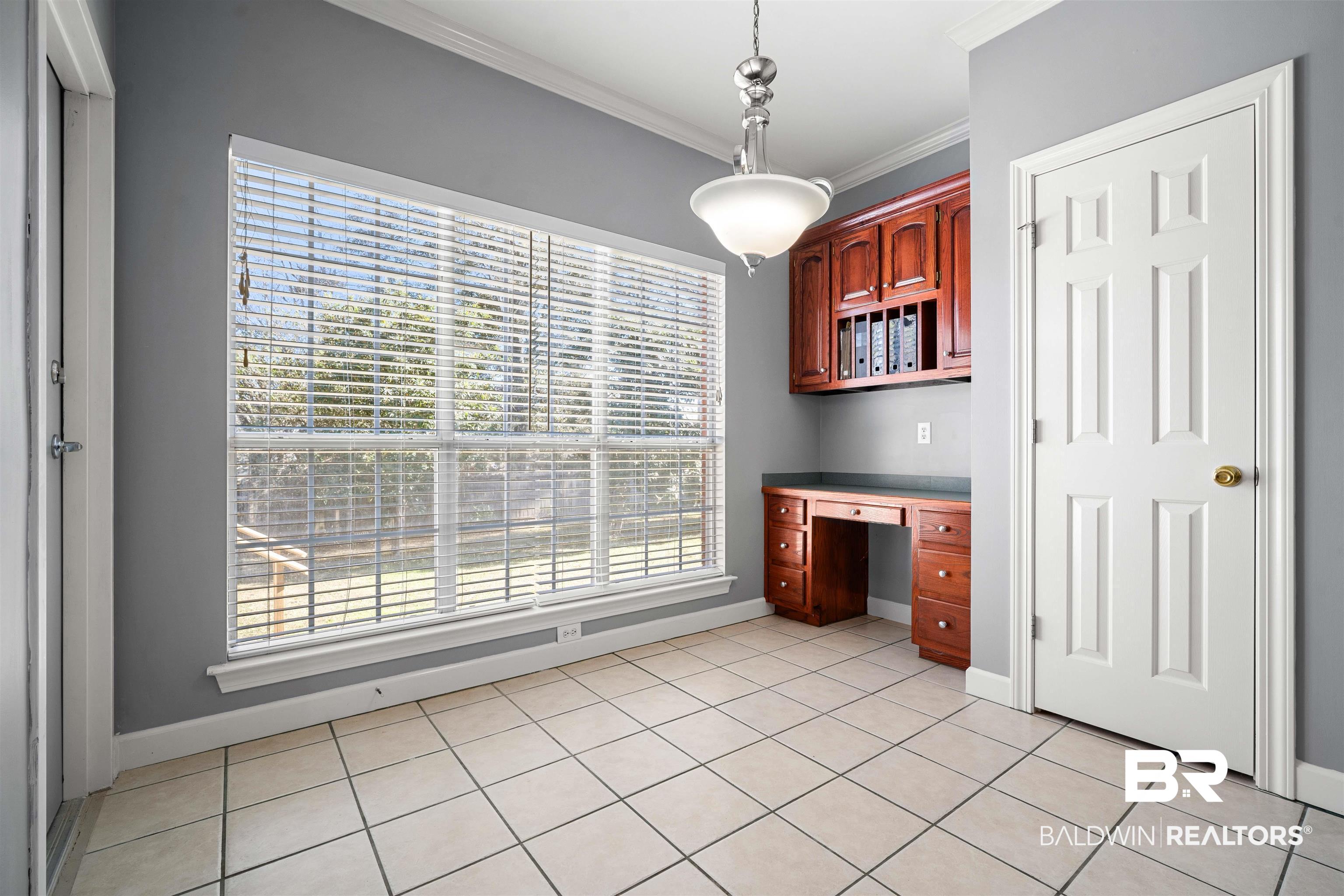 615 Summerlake Place Mobile, AL 36608 - Photo 12 of 35 Unfurnished dining area with built in study area, crown molding, and light tile patterned flooring