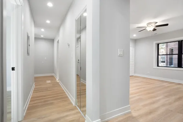 a view of a hallway with wooden floor and chandelier