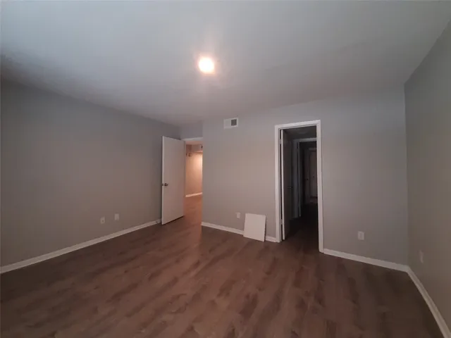 a view of an empty room with wooden floor and closet