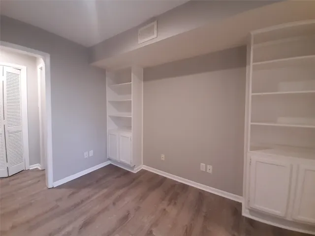 a view of an empty room with closet and wooden floor