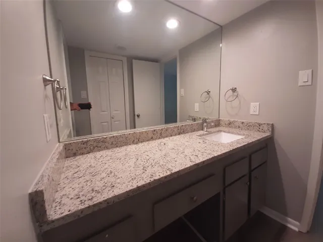 a bathroom with a granite countertop sink and a mirror
