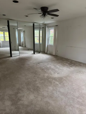 en empty room with windows and ceiling fan