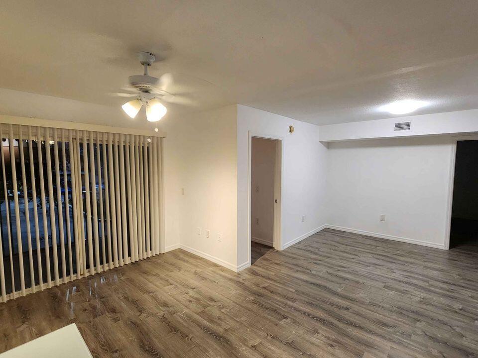 4081 San Marino Boulevard, Unit 203 West Palm Beach, FL 33409 - Photo 2 of 9 an empty room with wooden floor fan and windows