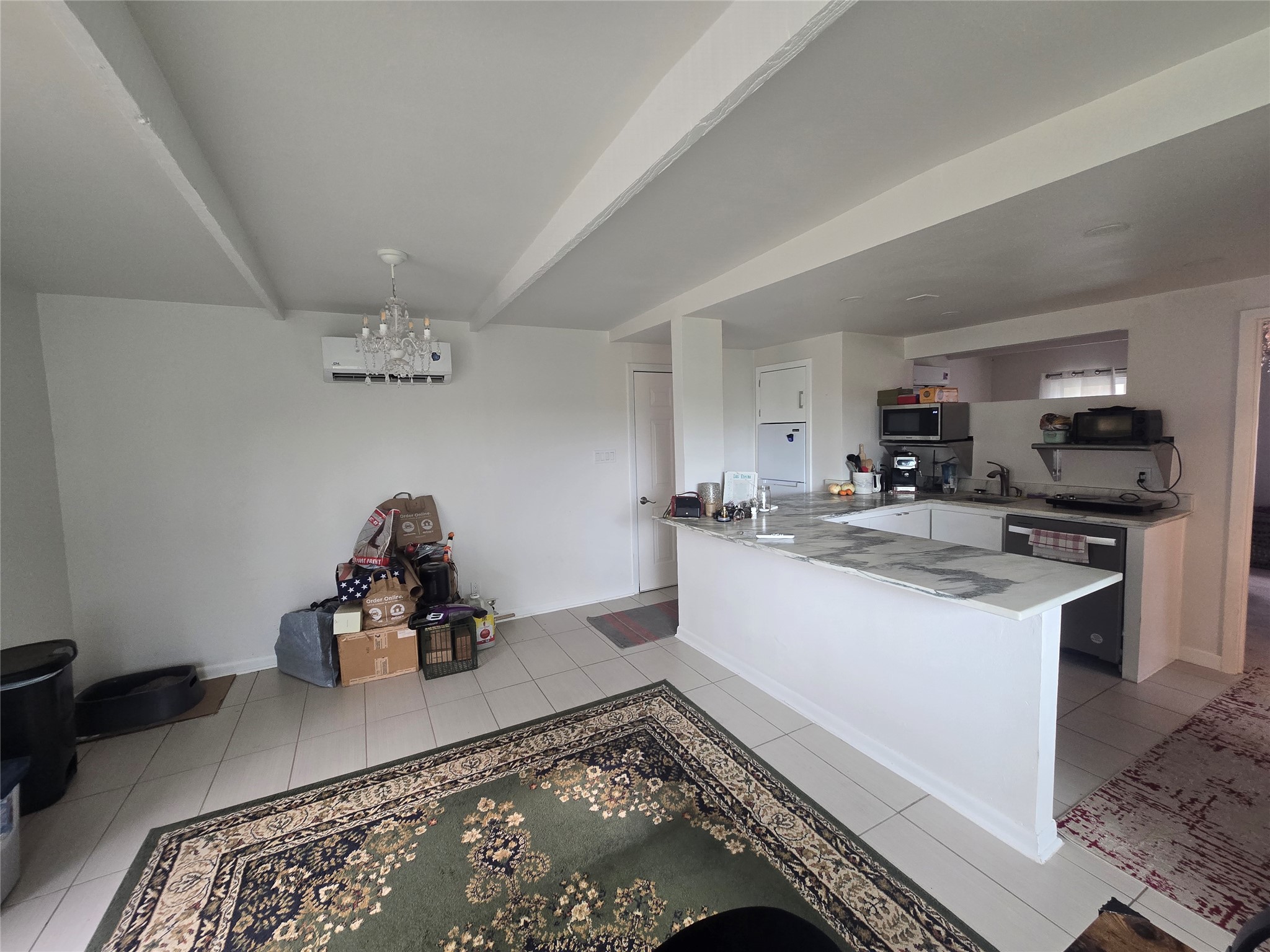 1106 The High Road, Unit A Austin, TX 78746 - Photo 2 of 12 Kitchen featuring a peninsula, light countertops, black microwave, stainless steel microwave, and a chandelier