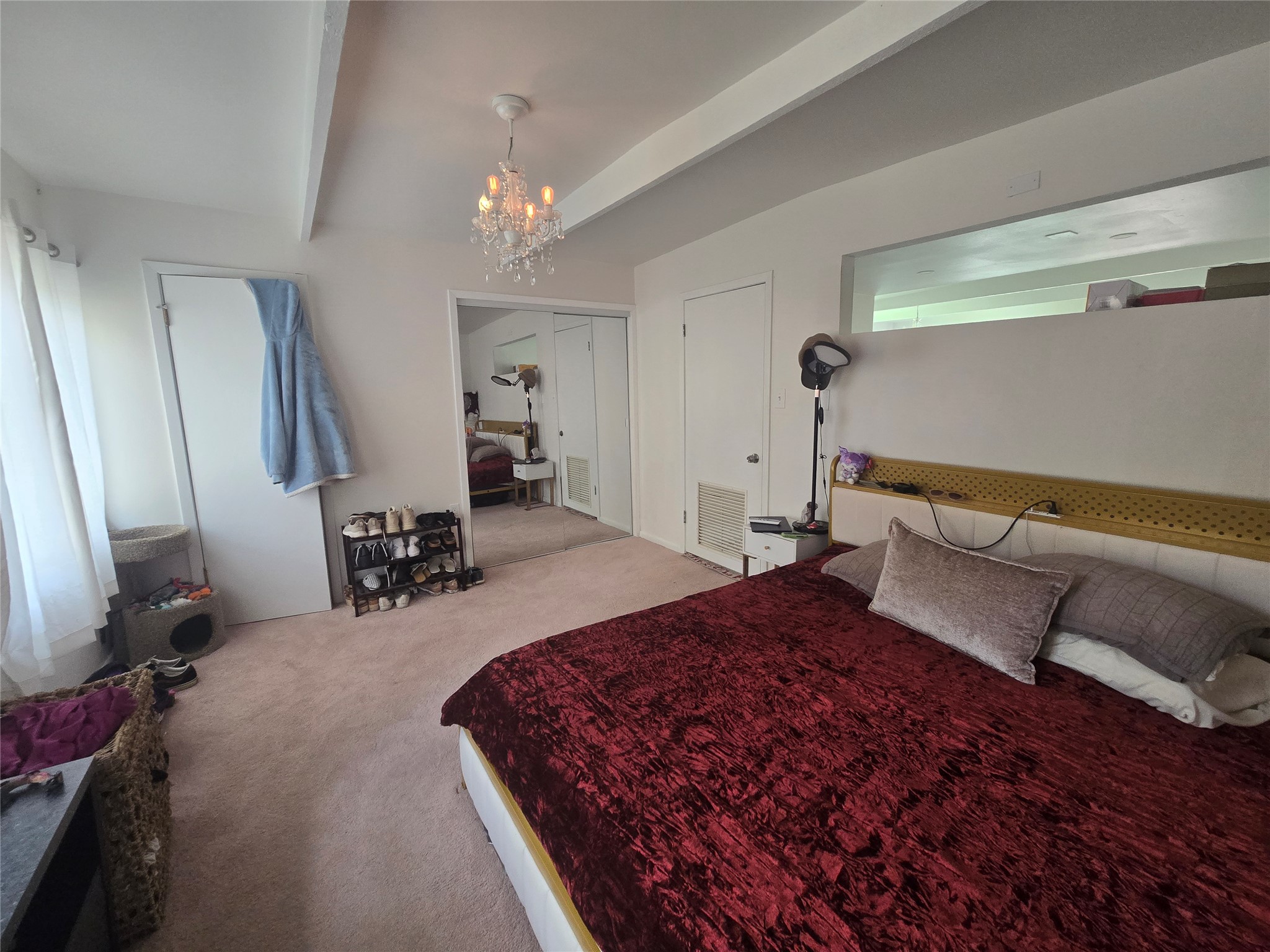 1106 The High Road, Unit A Austin, TX 78746 - Photo 5 of 12 Bedroom featuring suspended lighting, light carpet, beamed ceiling, and a closet