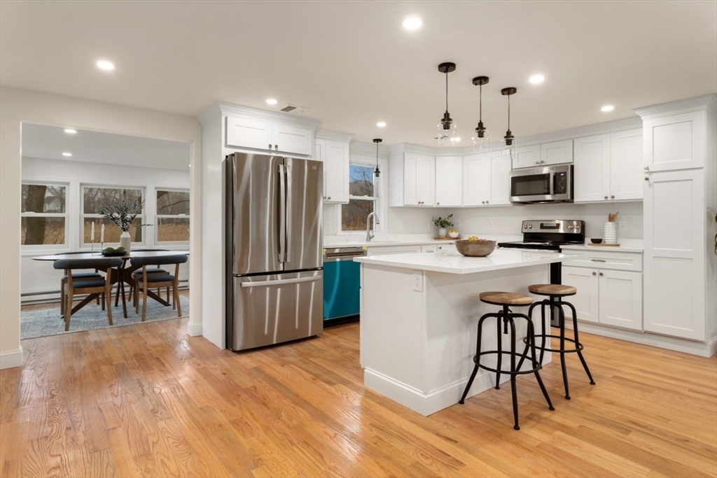 83 Riverbank Road Saugus, MA 01906 - Photo 15 of 36 a kitchen with stainless steel appliances granite countertop a refrigerator a stove a sink a microwave and white cabinets with wooden floor