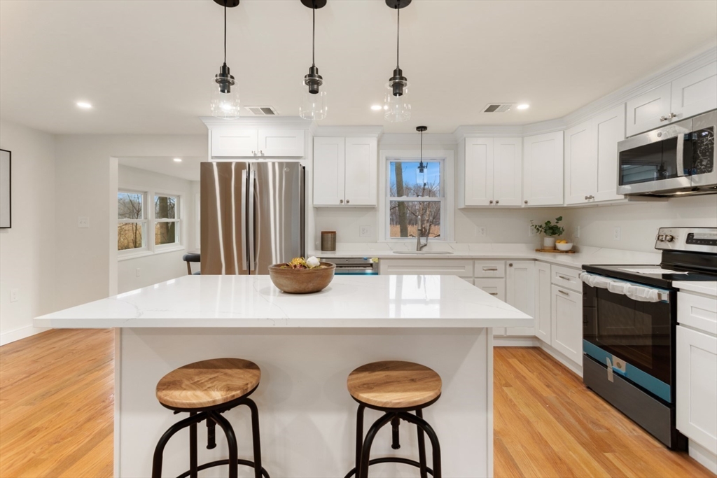 83 Riverbank Road Saugus, MA 01906 - Photo 16 of 36 a kitchen with stainless steel appliances granite countertop a sink a stove a refrigerator and chairs with wooden floor