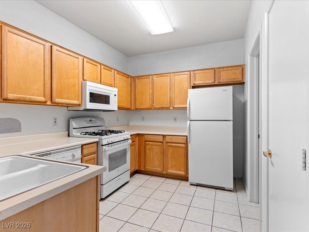 8725 West Flamingo Road, Unit 235 Las Vegas, NV 89147 - Photo 20 of 22 Kitchen with white appliances, light countertops, light tile patterned floors, and light brown cabinetry