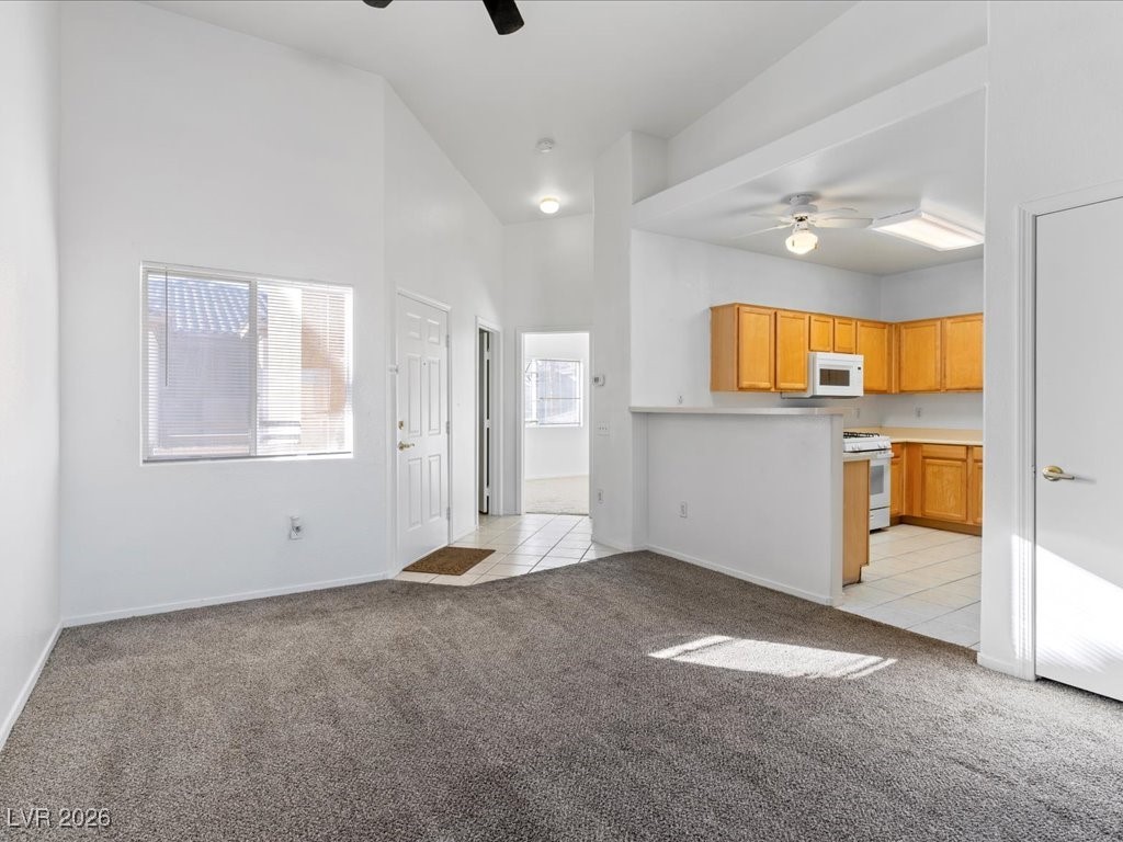 8725 West Flamingo Road, Unit 235 Las Vegas, NV 89147 - Photo 6 of 22 Unfurnished living room featuring ceiling fan, light carpet, a high ceiling, and light tile patterned floors