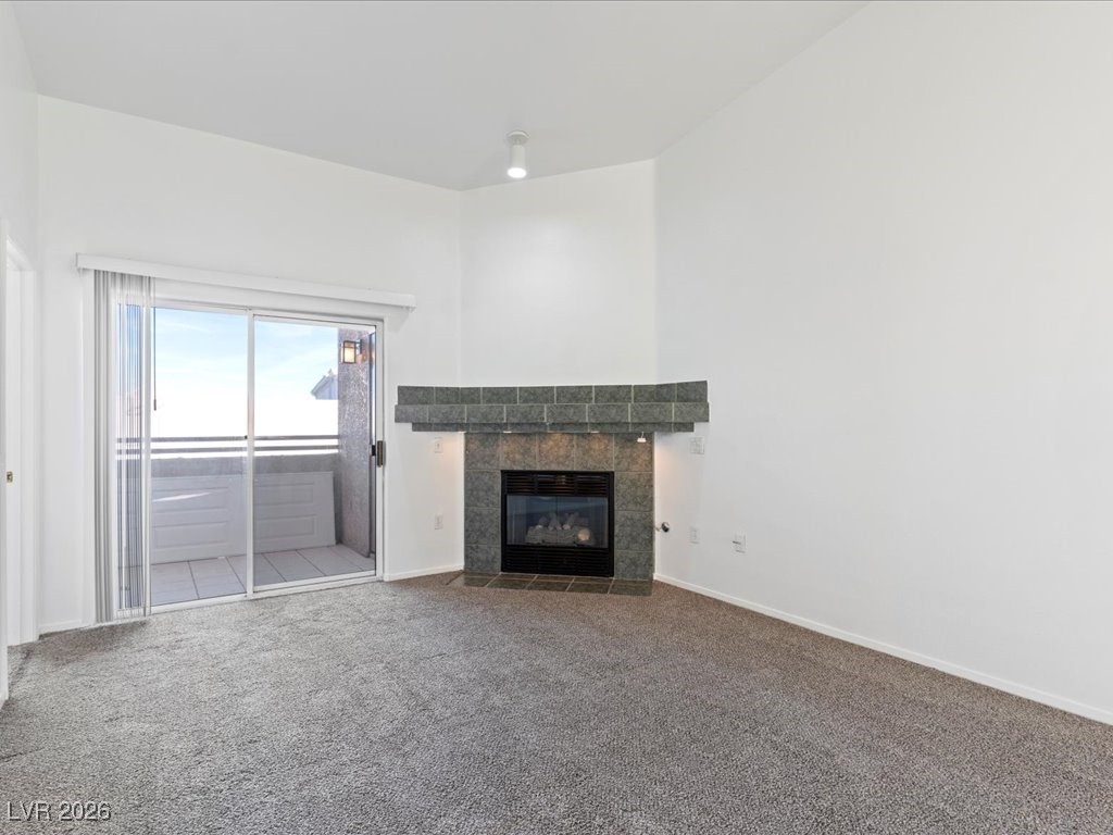 8725 West Flamingo Road, Unit 235 Las Vegas, NV 89147 - Photo 8 of 22 Unfurnished living room featuring a tile fireplace and carpet floors