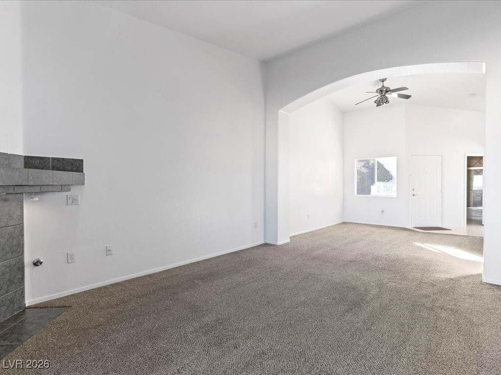 8725 West Flamingo Road, Unit 235 Las Vegas, NV 89147 - Photo 9 of 22 Unfurnished living room featuring carpet flooring, arched walkways, and ceiling fan