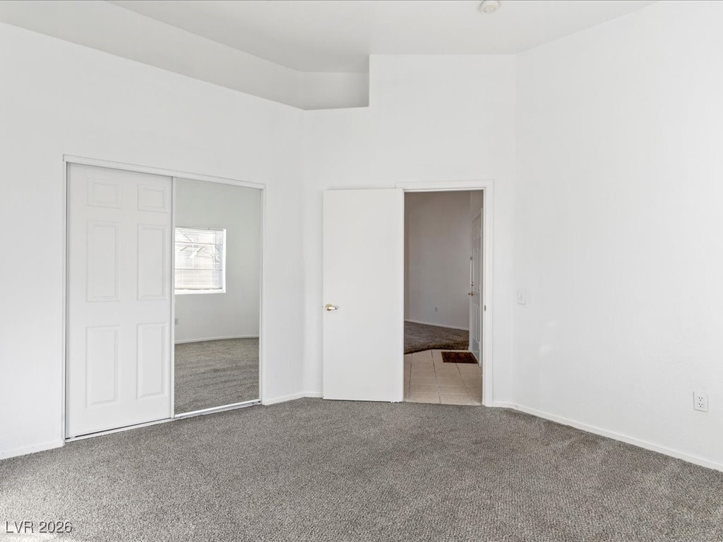 8725 West Flamingo Road, Unit 235 Las Vegas, NV 89147 - Photo 10 of 22 Unfurnished bedroom with light carpet, a towering ceiling, and a closet
