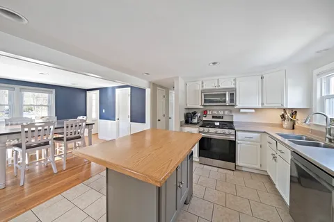 a kitchen with stainless steel appliances granite countertop a stove top oven a sink a dining table and chairs with wooden floor