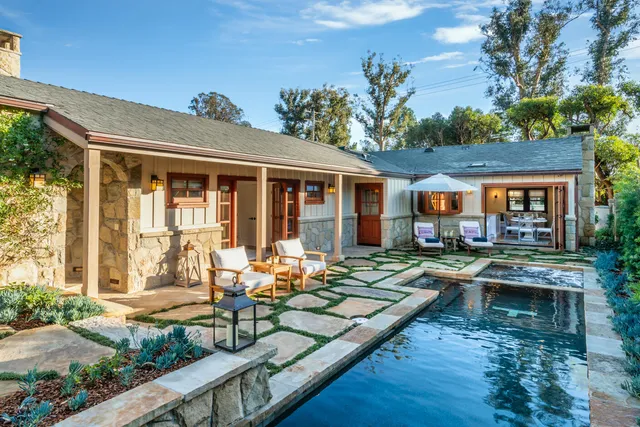 a front view of a house with swimming pool lawn chairs and wooden fence