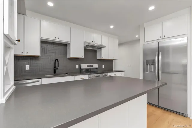 a kitchen with stainless steel appliances granite countertop a sink a stove and a refrigerator