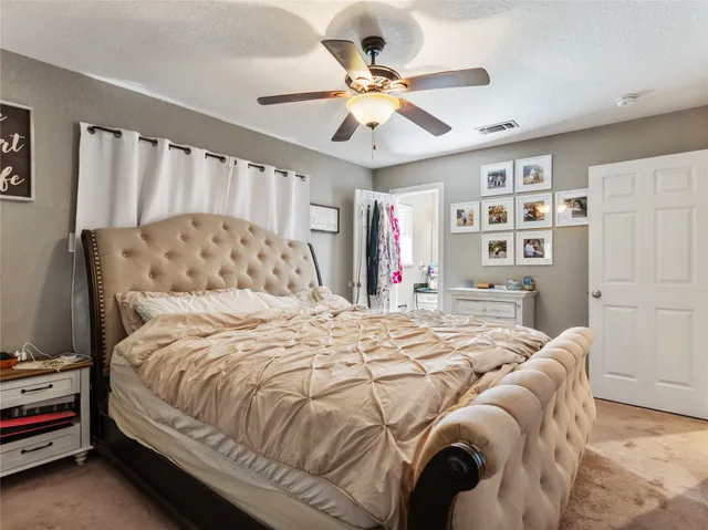 a bedroom with a large bed a flat tv screen and a ceiling fan