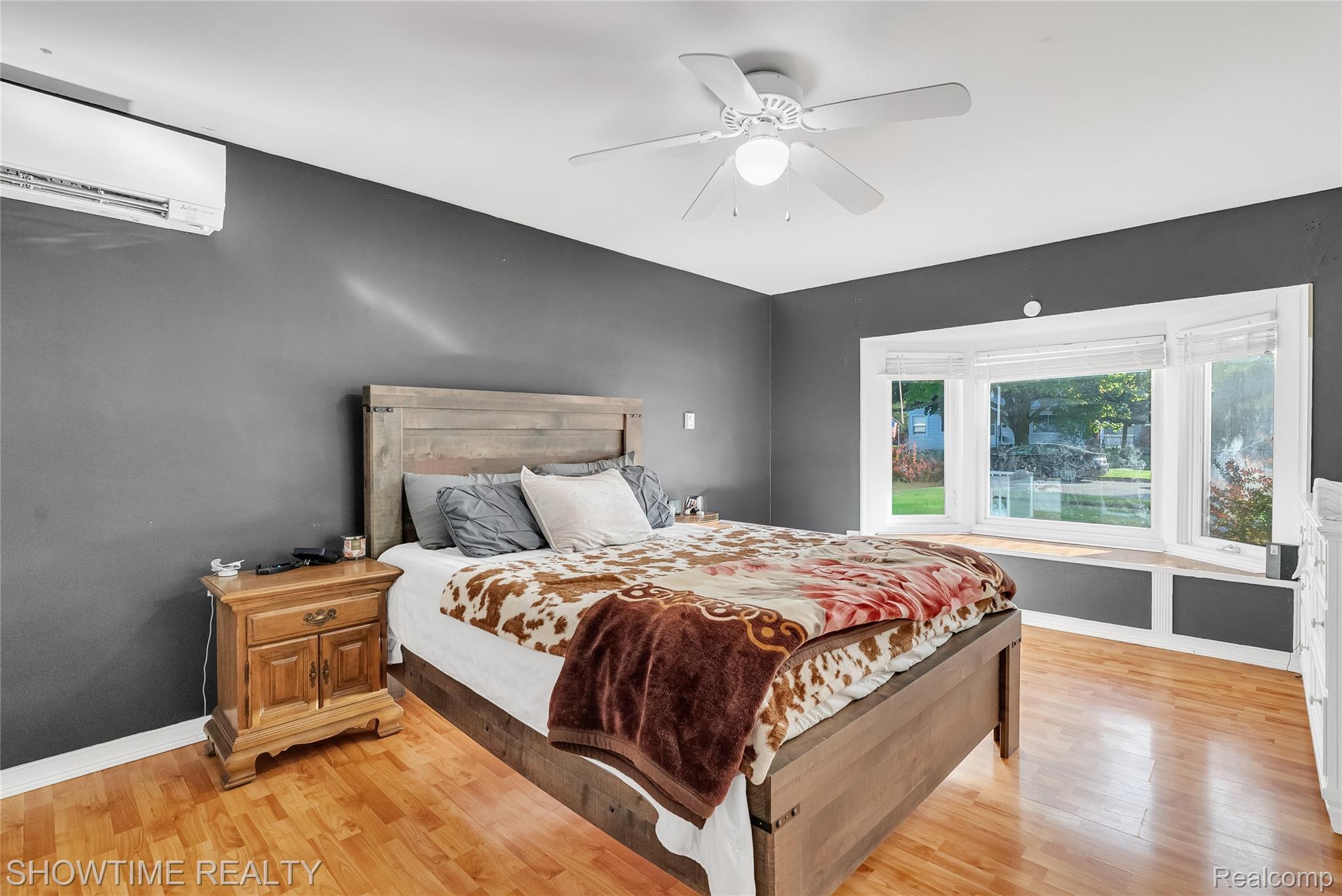 3444 Maple Street Port Huron, MI 48060 - Photo 16 of 30 Bedroom featuring wood-finish flooring, a contemporary ceiling fan, dark gray walls, and a multi-pane bay window with a window seat